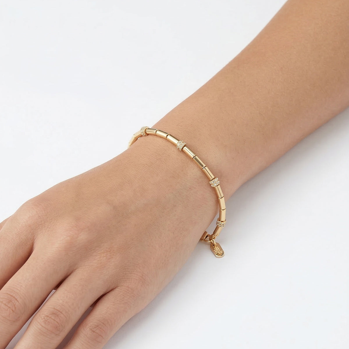 PULSERA COLOR  DORADO, RALPH LAUREN, FORMA CIRCULAR  TIPO FLEXIBLE CON CRISTALES TRANSPARENTES, CIERRE TIPO PINZA AJUSTABLE , FAMILIA LINDELLA, CONTENIDO 1 PULSERA